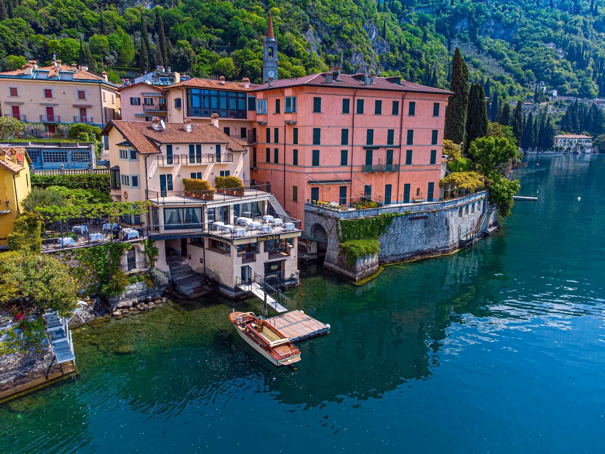 A hotel front of lake como, with pink buildings and a boat