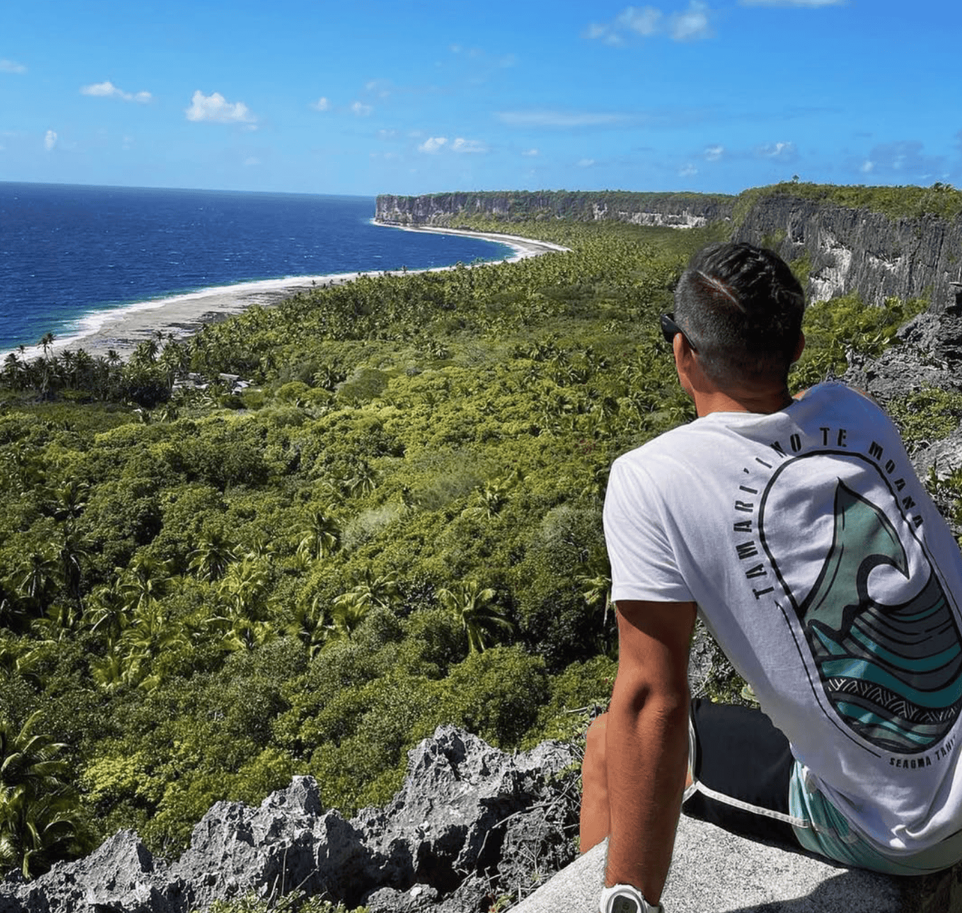 a man sitting on a cliff overlooking a body of water