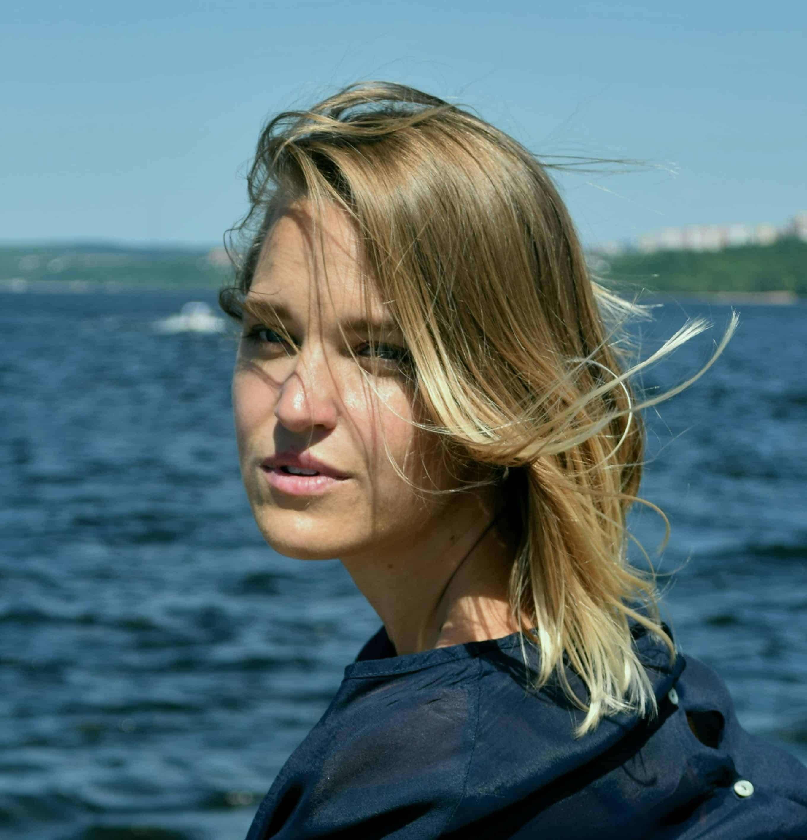 A woman with sun-kissed blonde hair enjoying a scenic ocean view, embodying freedom and adventure on the waters. Perfect for travel, coastal exploration, and oceanic photography enthusiasts.