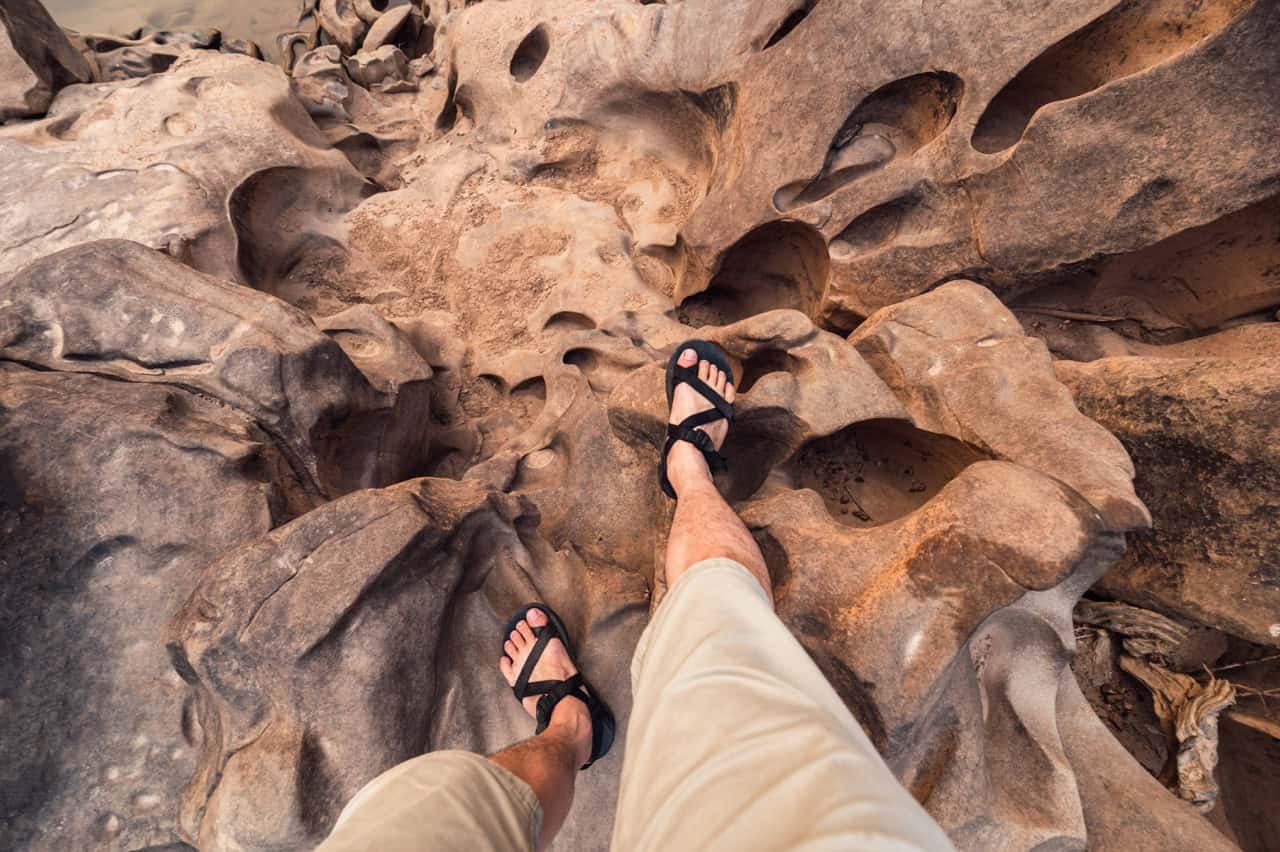 Point of view of Man legs with hiking shoes standing on rugged rock